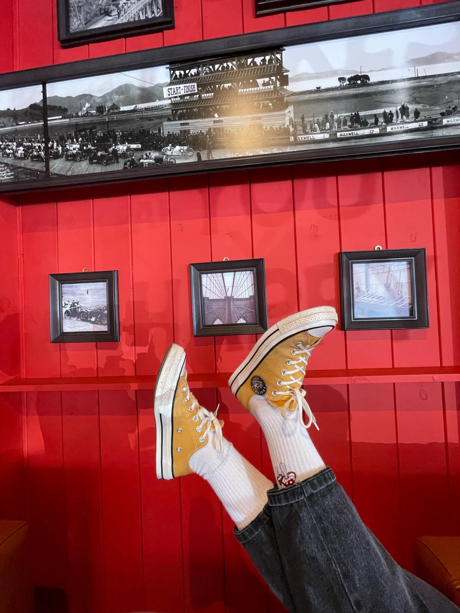 Kırmızı panel duvar ve nostaljik fotoğraf çerçeveleri önünde sarı spor ayakkabılar